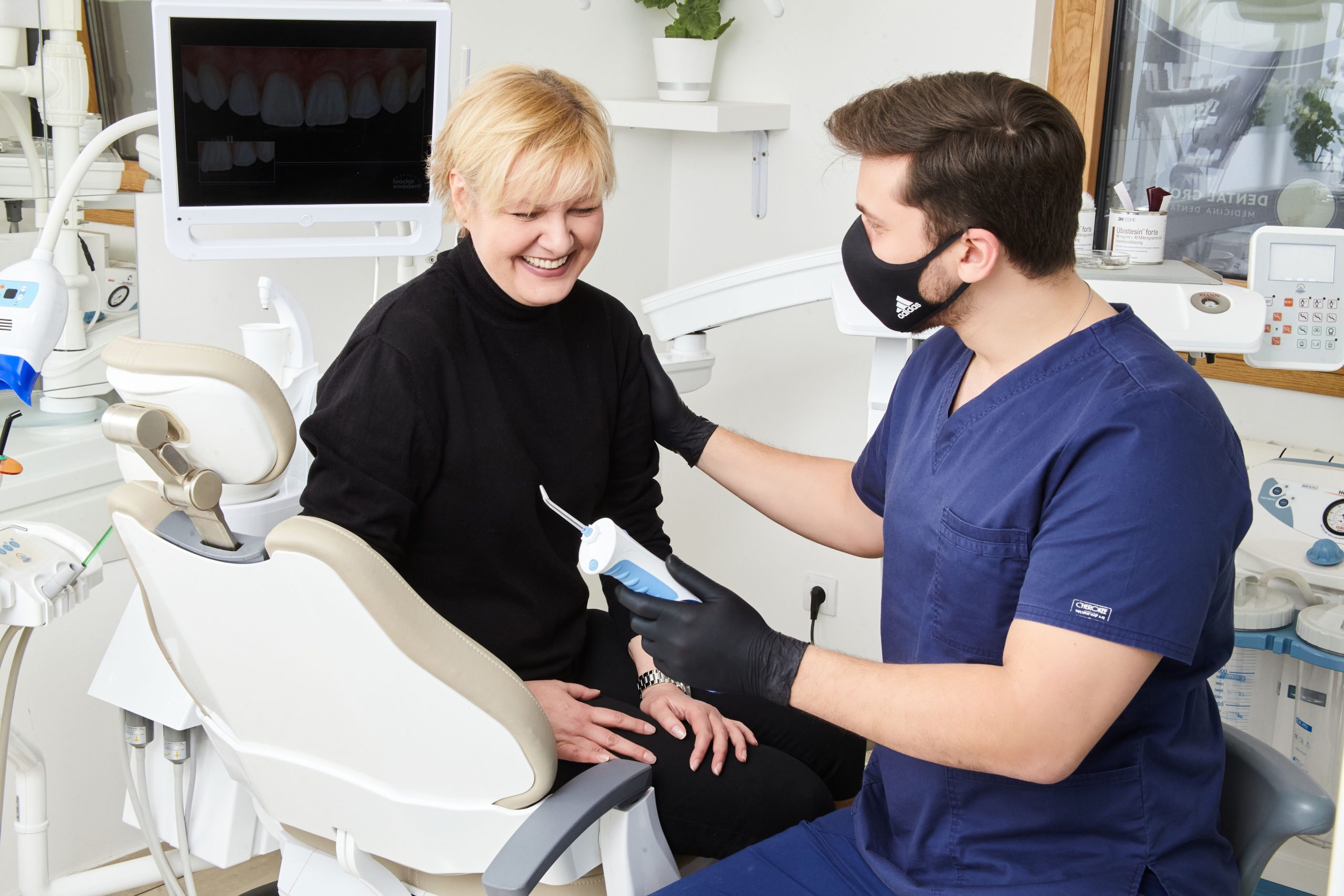Dentist explaining a dental implant model to a patient